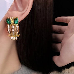 Detail of vintage owl earring featuring green gem eyes and sparkling rhinestone body