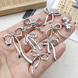 Silver bow pendants set for DIY necklaces and bracelets on hand showing 7 styles