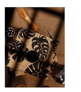 Vintage brown kraft paper with black monstera leaf pattern wrapping a gift box