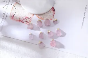 Close-up of ten irregular rose quartz crystal pendants with gold edges on white background