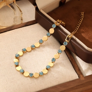Detailed shot of golden round link bracelet with light blue gemstones on jewelry box