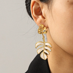 Elegant gold leaf earrings with white enamel finish on a model for a luxury jewelry look