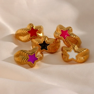 Macro detail of five multi-colored star rings with gold bands on silk background