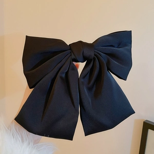 Détail d'une grande pince à cheveux avec nœud en soie noire pour une coiffure chic