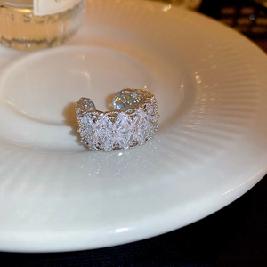 Macro shot of silver lace ring with sparkling cubic zirconia on white ceramic tray