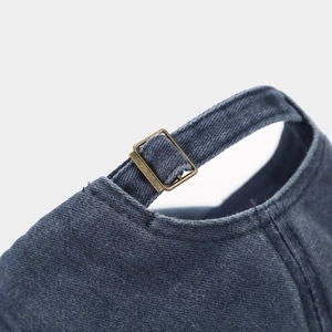 Detail of adjustable vintage bronze buckle on blue washed denim baseball cap