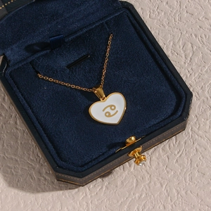 Macro shot of Cancer zodiac heart pendant in gold finish inside a blue velvet jewelry box