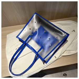 Detailed view of clear PVC tote bag with royal blue leather trim and colorful rhinestones