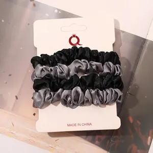 Detail of 4-pack satin hair scrunchies in black and grey on a display card