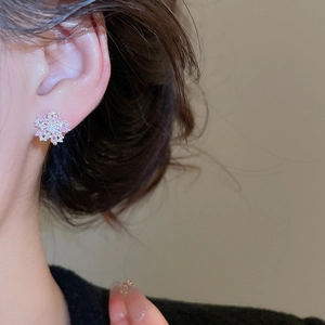 Close-up of elegant pink and white zircon flower studs worn on a female ear