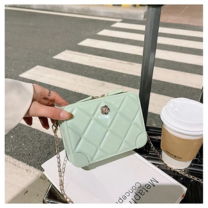 Detail of mint green PVC jelly bag with quilted texture and flower clasp in a travel setting