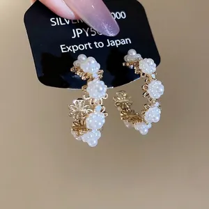 Double-layer circular pearl flower stud earrings in gold-tone finish on display card