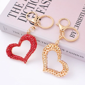 Luxury heart-shaped gold keychains with red rhinestones on Dior book background