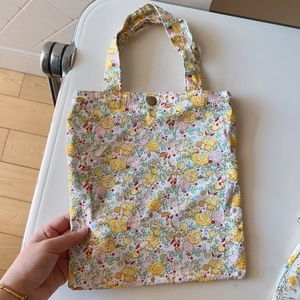 Detailed view of yellow floral cotton tote bag featuring metal snap closure and dual handles