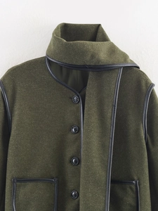 Detailed close-up of dark green wool coat with black leather piping and scarf collar