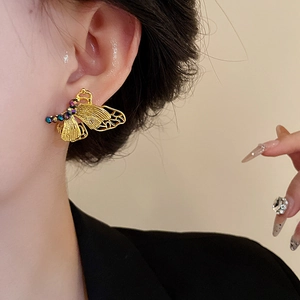 Close-up of butterfly stud earring featuring intricate cutouts and colorful pavé crystals