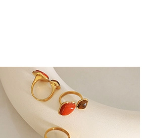 Close-up of gold open rings with orange and tiger eye semi-precious stones