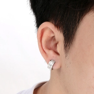 Close-up of titanium steel huggie earring with cross relief and Roman numerals on ear