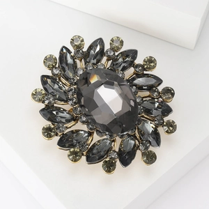 Macro detail of a vintage gold brooch featuring a large faceted dark gray crystal center