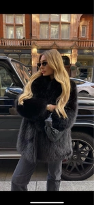 Vue détaillée d'un manteau en fausse fourrure noire de luxe avec un sac tissé élégant
