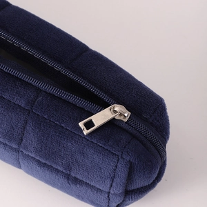 Close-up of dark blue velvet pencil case showing quilted texture and silver zipper detail