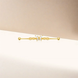 Detail of a golden industrial barbell with a butterfly charm set with marquise zircons