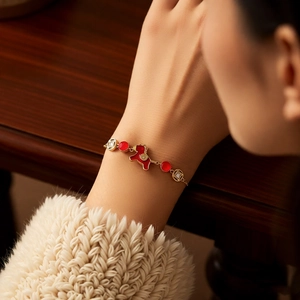 Vue détaillée du bracelet doré avec breloque cheval et perles rouges sur un poignet