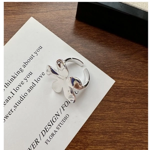 Gros plan d'une bague fleur abstraite en argent poli avec finition miroir sur carte