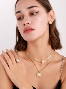 Close-up of golden spiral jewelry set featuring necklaces, earrings and ring with pearls
