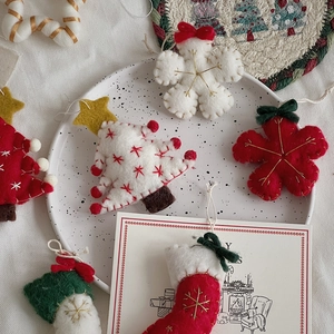 Flat lay of wool felt Christmas ornaments with trees, snowflakes, and stockings on a plate