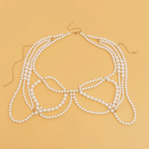 Detailed view of multilayer pearl body chain with golden chains on a warm yellow background