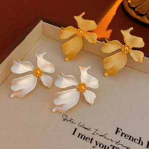 Detail of vintage matte metal flower earrings in gold and white floral styles