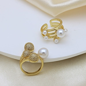 Gold plated open rings with pearls and zircon spheres on elegant silk background