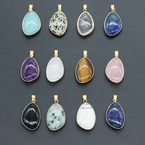 Assorted natural crystal teardrop pendants with gold plated edges on grey background