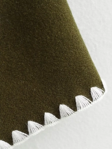 Detail of dark olive wool jacket featuring white triangular decorative stitching on edges