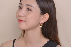 Detailed view of model wearing a vintage gold earring with large oval amber gemstone