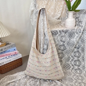 Close-up of cream crochet tote bag featuring colorful threads and shell tassel fringe detail