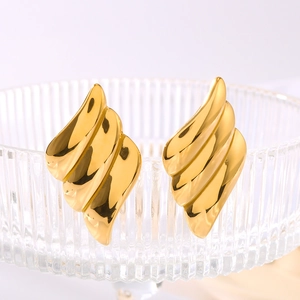 Polished 18k gold plated stainless steel wing-shaped earrings on glass background