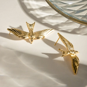 Elegant 18k gold plated stainless steel swallow bird stud earrings on stone surface