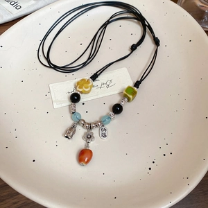 Macro detail of Chinese ethnic necklace featuring ceramic beads and Nafu silver charm