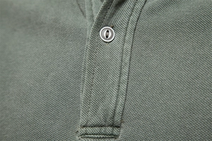 Macro detail of a grey-green piqué cotton polo shirt showing a marble button and texture