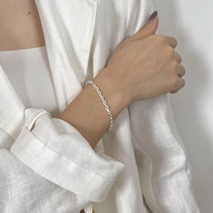 Close-up of a minimalist S925 sterling silver cross chain bracelet on a model wrist