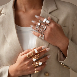 Détails de bagues géométriques superposables or et argent avec perles sur mains de mannequin