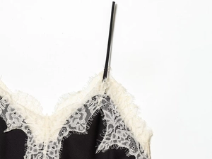 Close-up of black satin camisole with white eyelash lace trim and thin shoulder straps