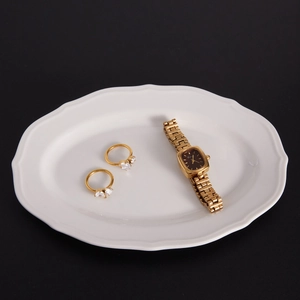 Détail de bagues dorées avec zircon et montre vintage en métal sur plateau blanc