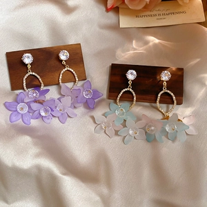 Detail view of ziron flower pendant earrings with matte petals on silk background