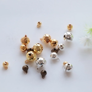 Flat lay of small gold, silver and bronze metal DIY craft bells on a white surface
