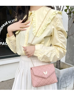 Détail du sac bandoulière matelassé rose avec fermoir papillon doré et chaîne en métal