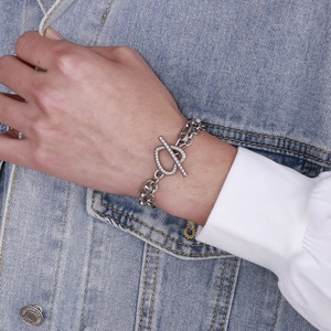 Close-up of stainless steel chain bracelet with a textured toggle clasp on a wrist