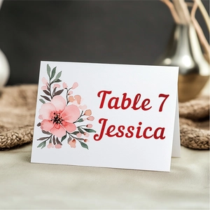 Foldable wedding table card with pink floral design on rustic linen background